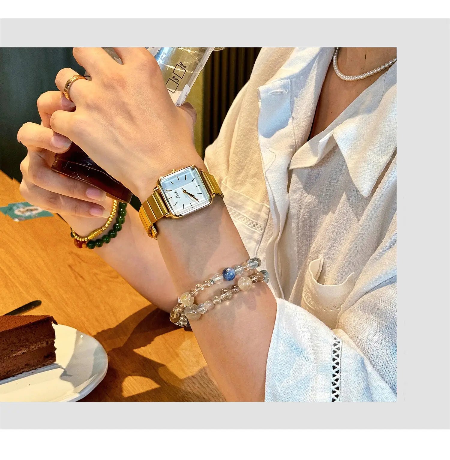 Women's gold-tone square-face wristwatch by Simples Market with metal strap and white dial.