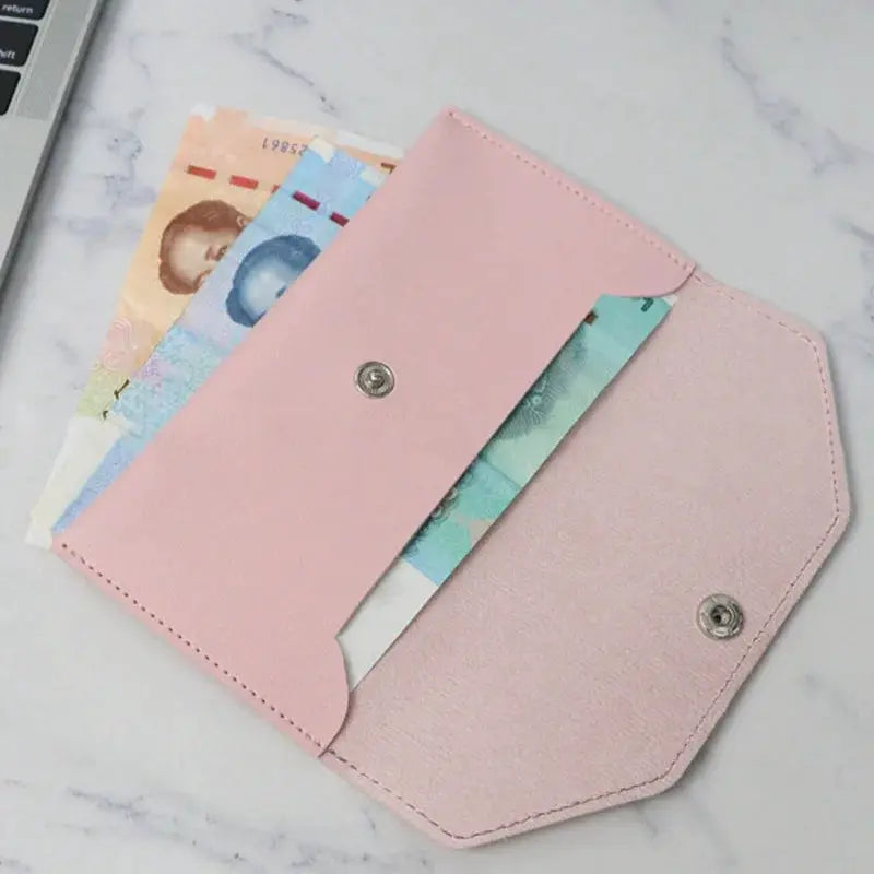 Pink leather envelope-style wallet with card slots, open to reveal banknotes