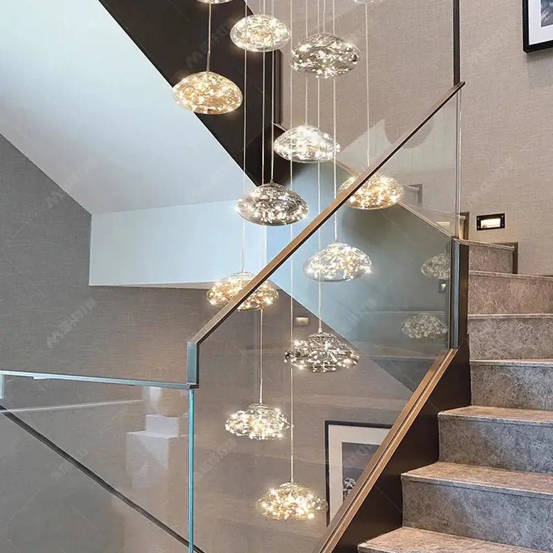 Pendant lights by Simples Market; glass globe pendants in gold and silver tones, clustered over a glass staircase.