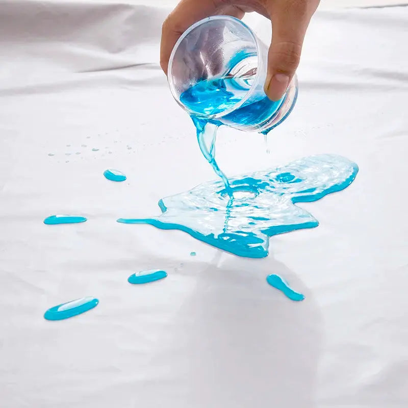 Simples Market TPU waterproof bed pad; blue liquid being poured onto white surface