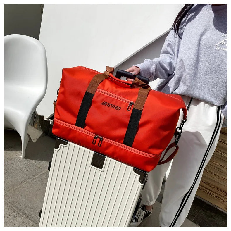 Large-capacity travel gym bag by Simples Market, red with brown handles, atop a silver suitcase