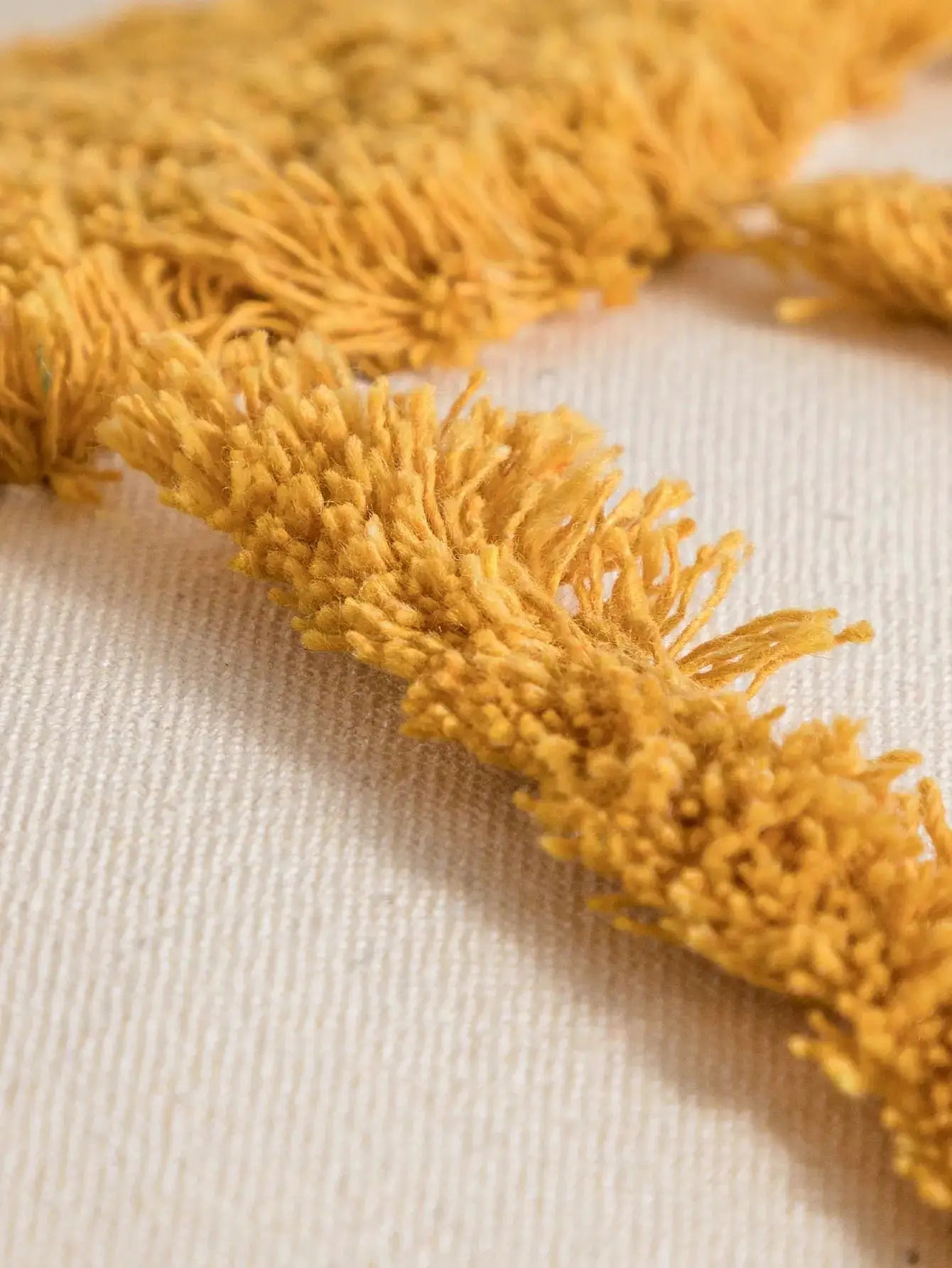 Yellow tassel pillowcase cover on beige cotton sail fabric with tufted trim