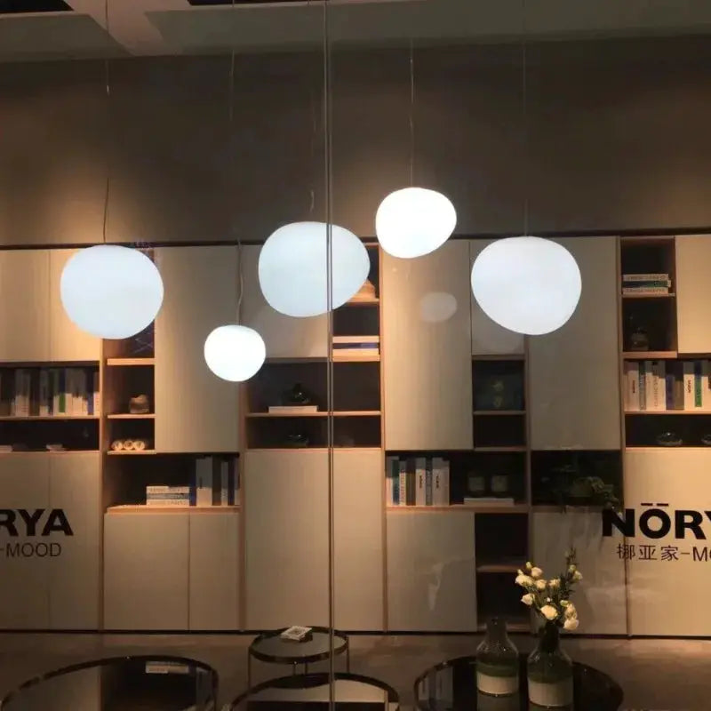 Nordic Creative White Glass Ball Pendant lights, a set of 5 spherical glass pendants hanging in a modern showroom
