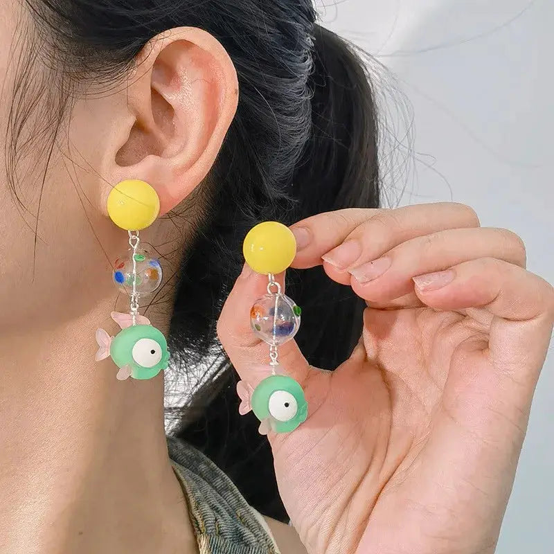 Pair of drop earrings with bright yellow round studs, clear speckled beads, and mint-green goldfish pendants