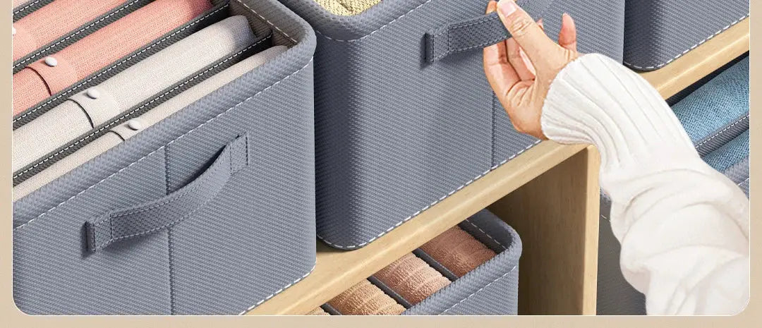 Three gray fabric storage boxes with handles on a wooden shelf, foldable wardrobe organizers