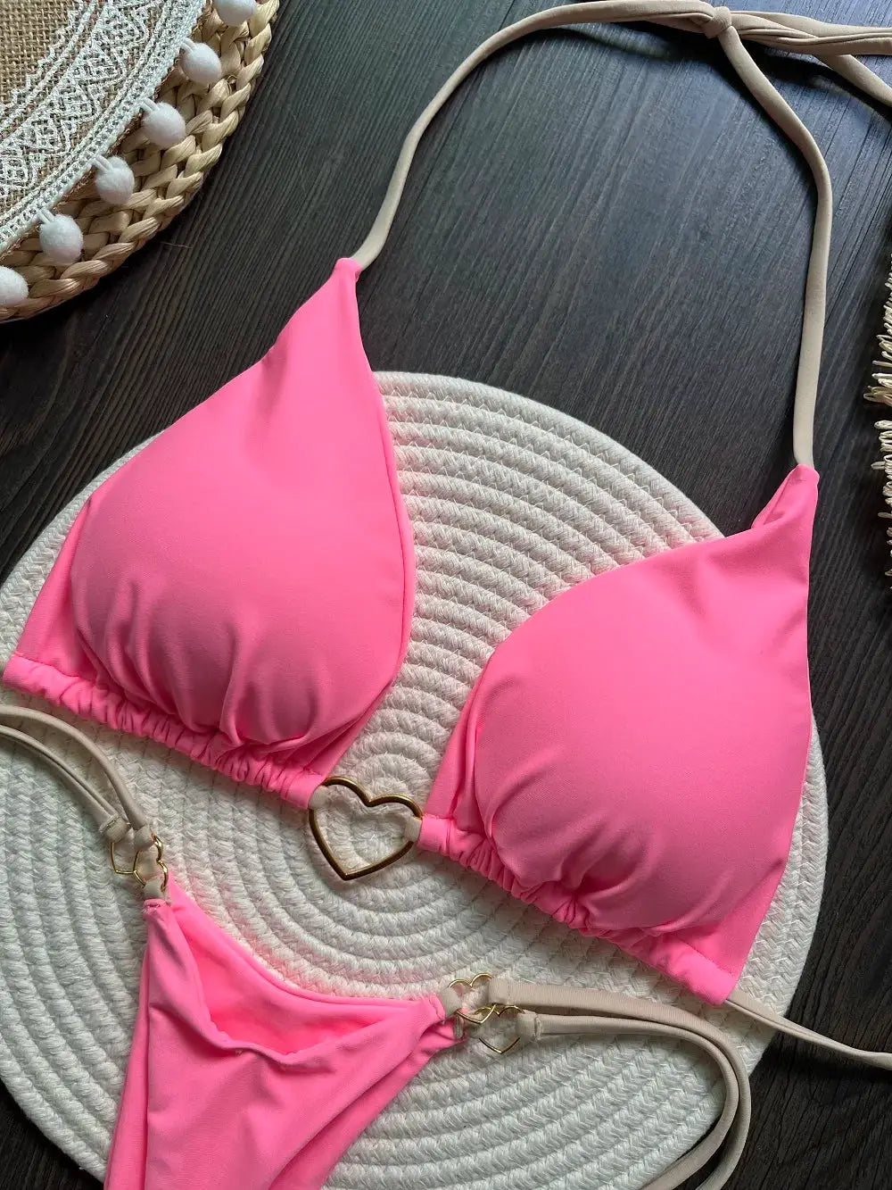 Pink halter bikini set with triangle top and thong bottoms, beige straps and gold heart rings.