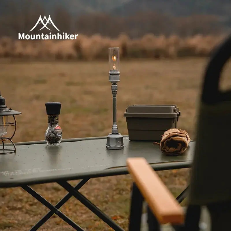 Mountainhiker outdoor gas light set on picnic table; silver metal lamp with glass chimney, Simples Market branding.