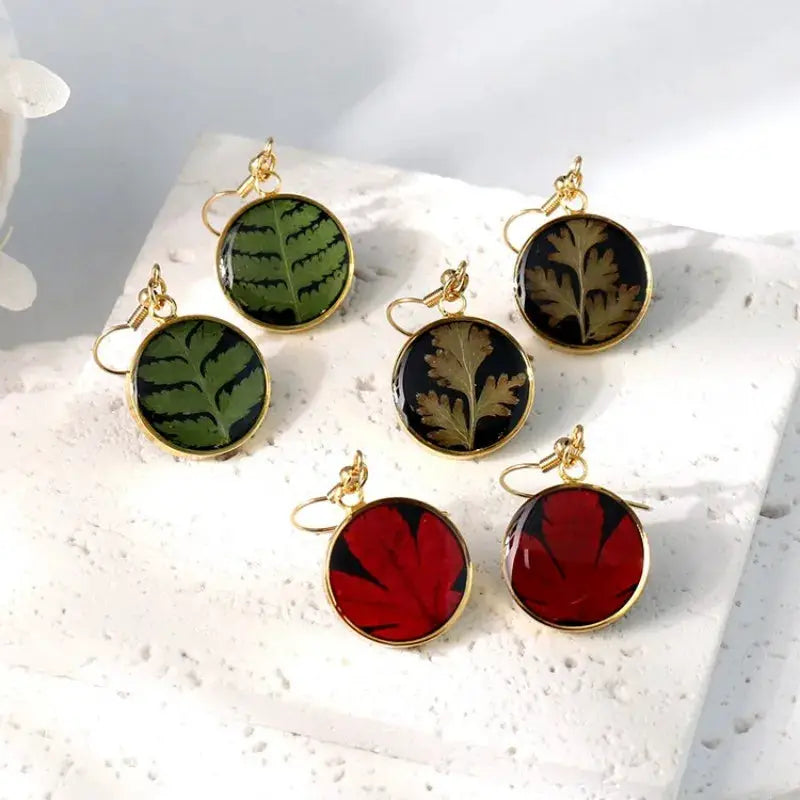 Pressed flower epoxy resin earrings, round gold-tone frames with green, black, and red leaf designs, set of 6