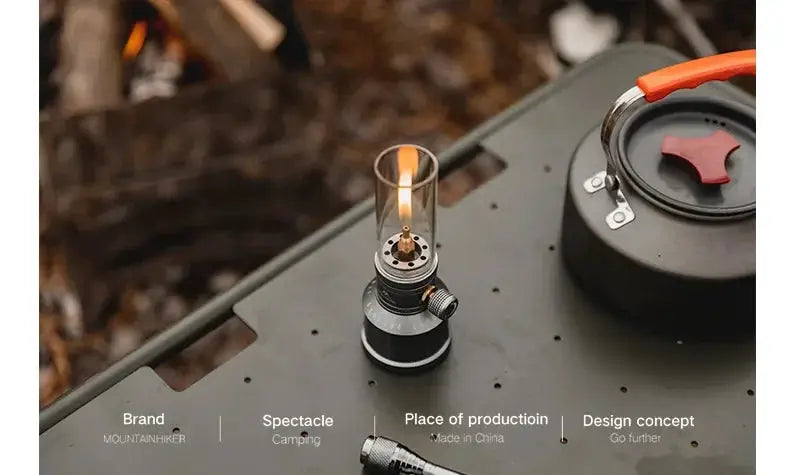 MOUNTAINHIKER outdoor gas light set on a camping table with black metal body and glass chimney.