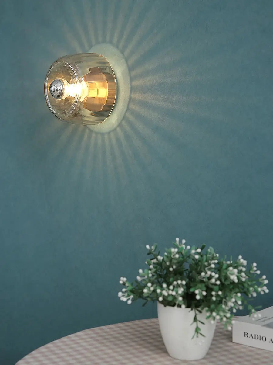 LED Bauhaus glass wall lamp; round clear sconce with warm LED on teal wall
