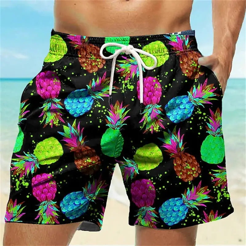 Men's beach shorts with neon pineapple graffiti print on black fabric and white drawstring.