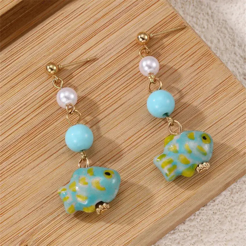 Pair of cute octopus earrings with turquoise glass octopus charms, white pearls, and gold-tone long drop design