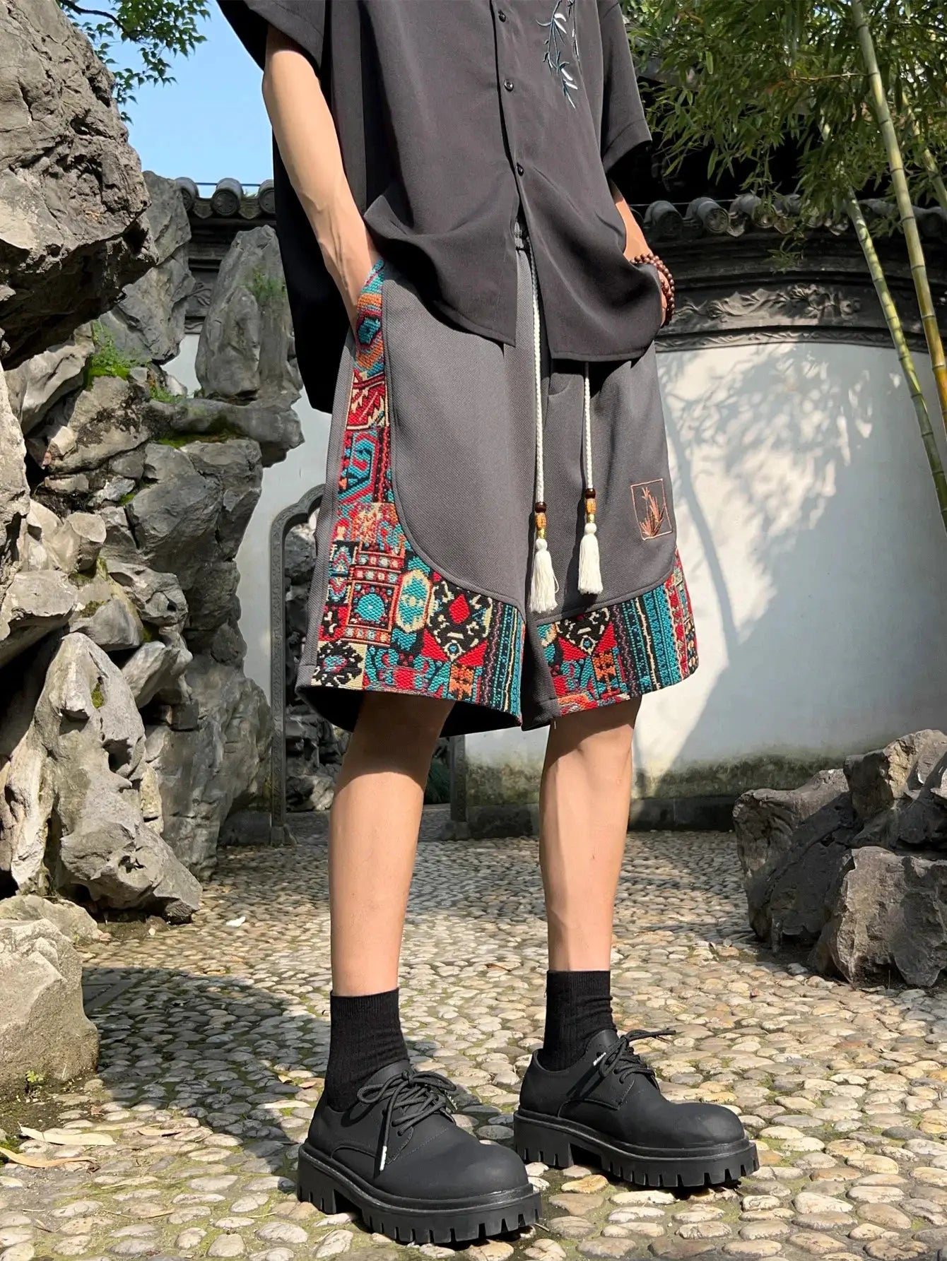 Men's ethnic embroidery shorts with pockets, grey fabric with colorful side panels and tassel-drawstring accents