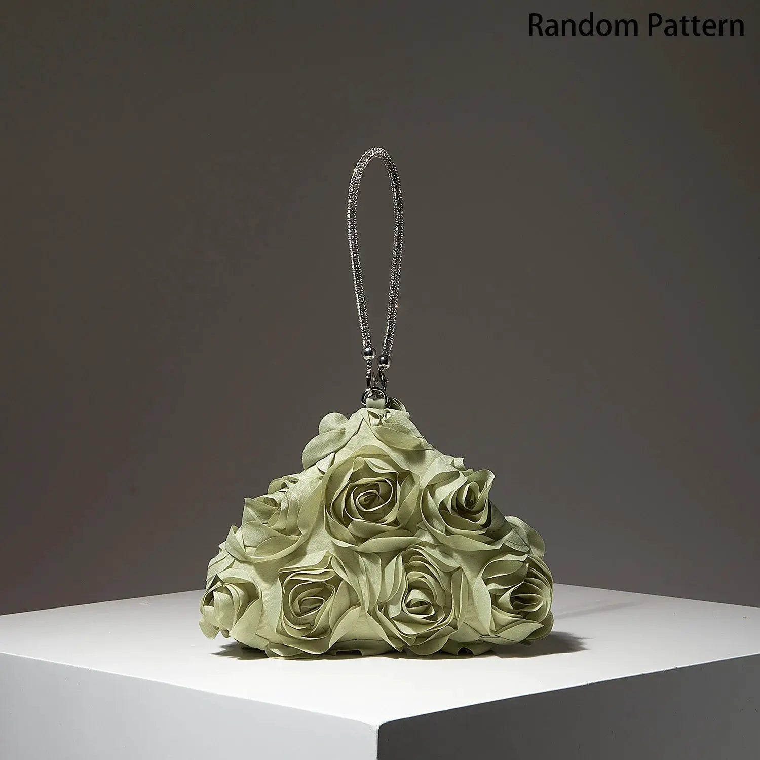 Mini purse with beaded silver strap atop a green fabric rose bouquet