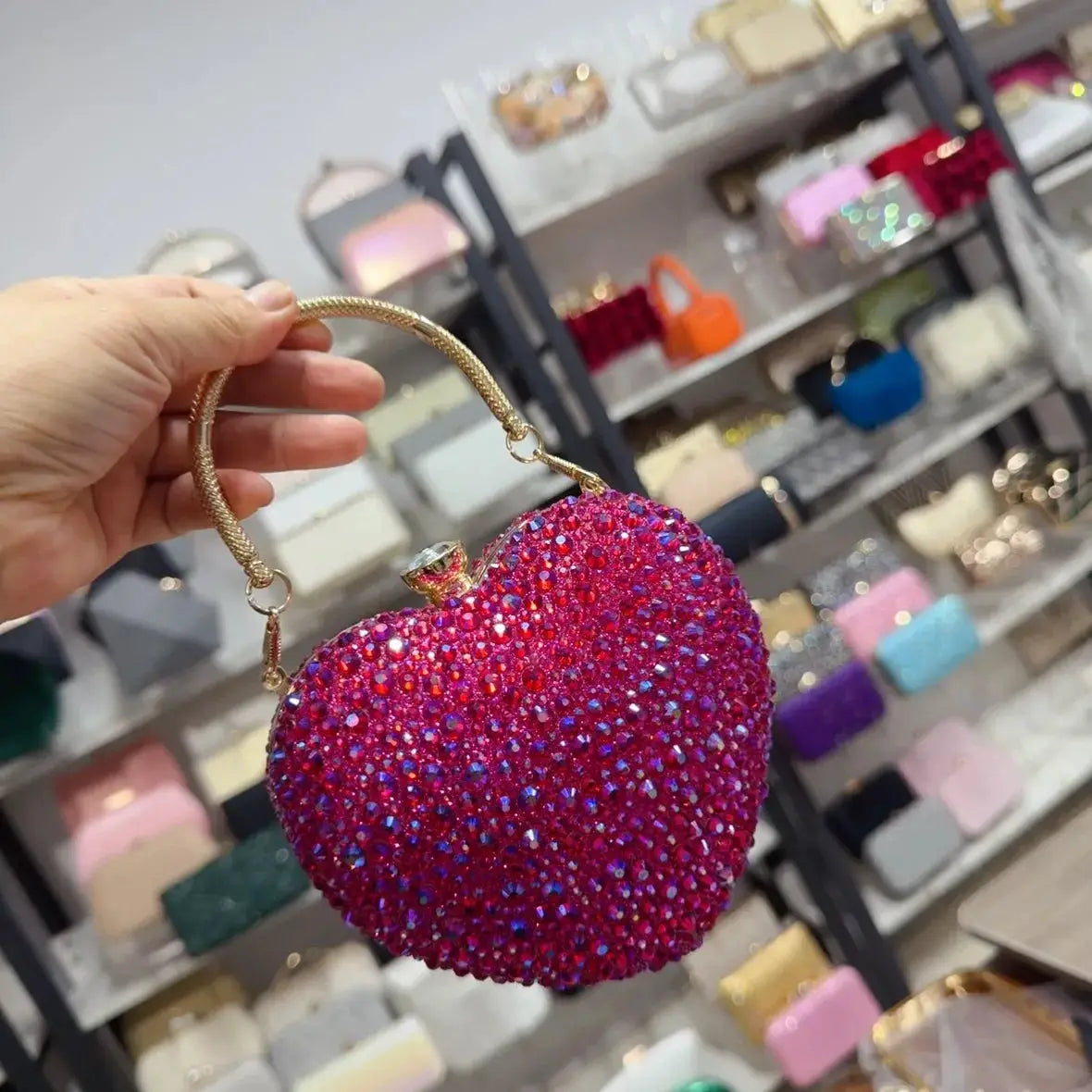 Heart-shaped crystal clutch purse encrusted with pink rhinestones and a gold handle