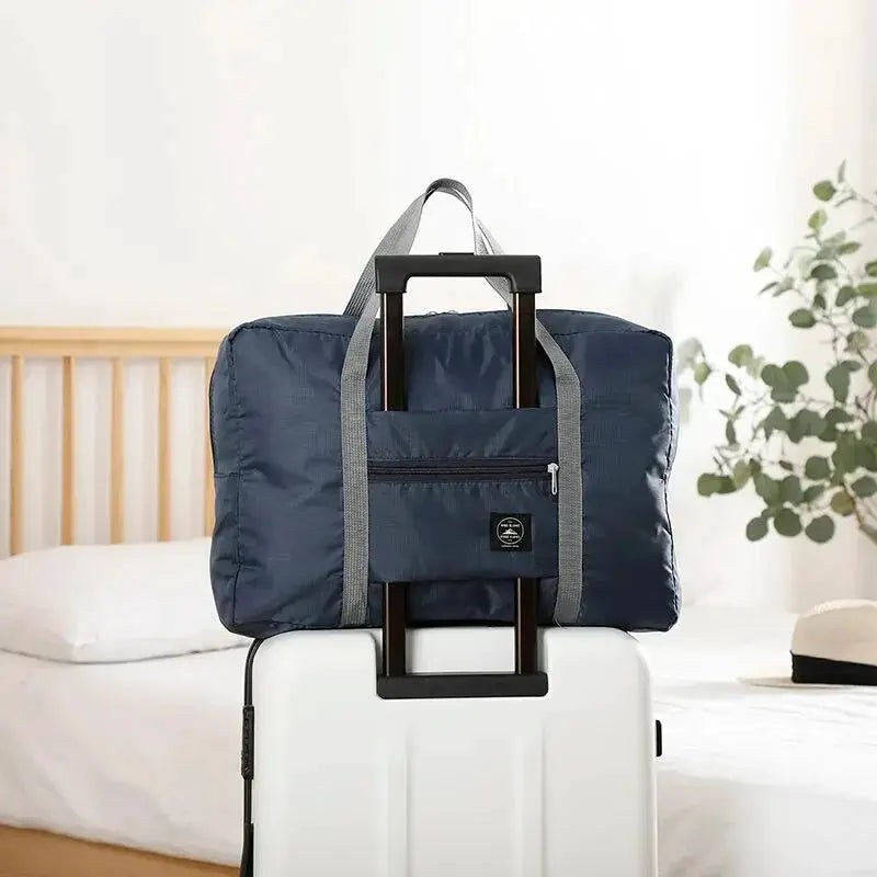 Navy blue foldable travel duffel bag with grey straps and front zip pocket