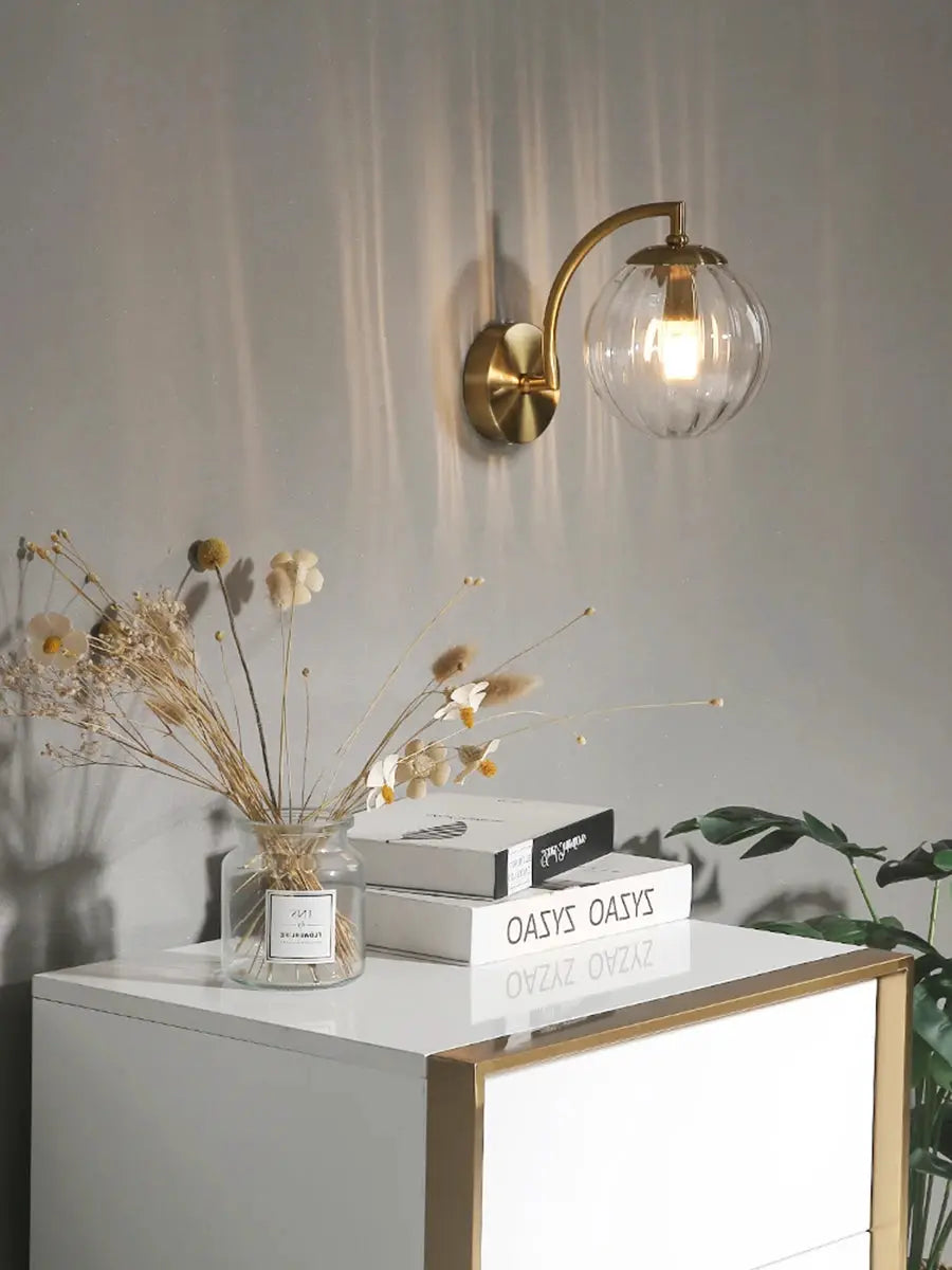 Modern LED wall lamp by Simples Market with glass globe shade and brass finish