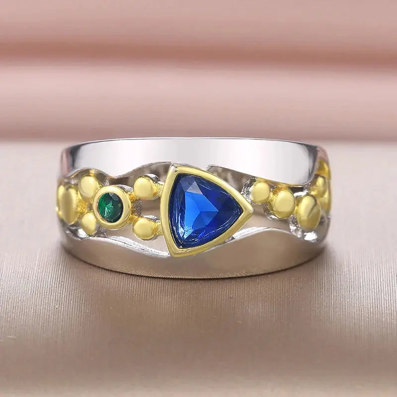 Huitan two-tone triangular blue-green CZ ring for women, silver band with gold-tone bezel and green accent stones.