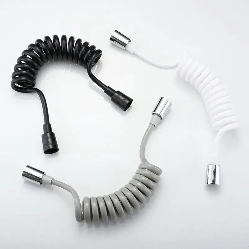 Three coiled handheld bidet sprayer hoses in black, white and gray with metal fittings