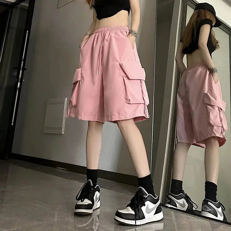 Pink women's high-waist cargo shorts with large side pockets and a loose wide-leg fit