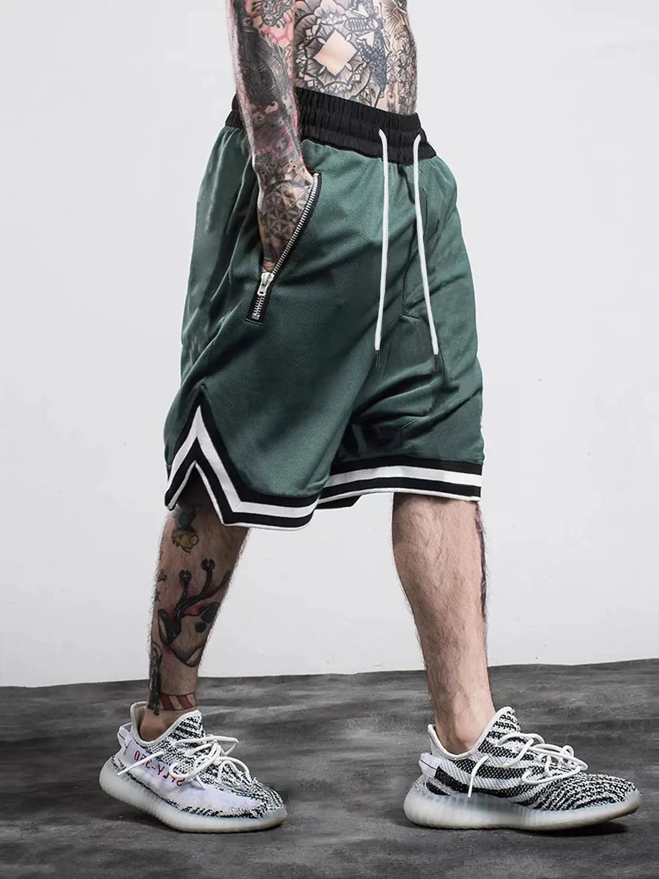 Simples Market men's green basketball shorts with black waistband, white drawstrings, zip pocket, and black-white trim.
