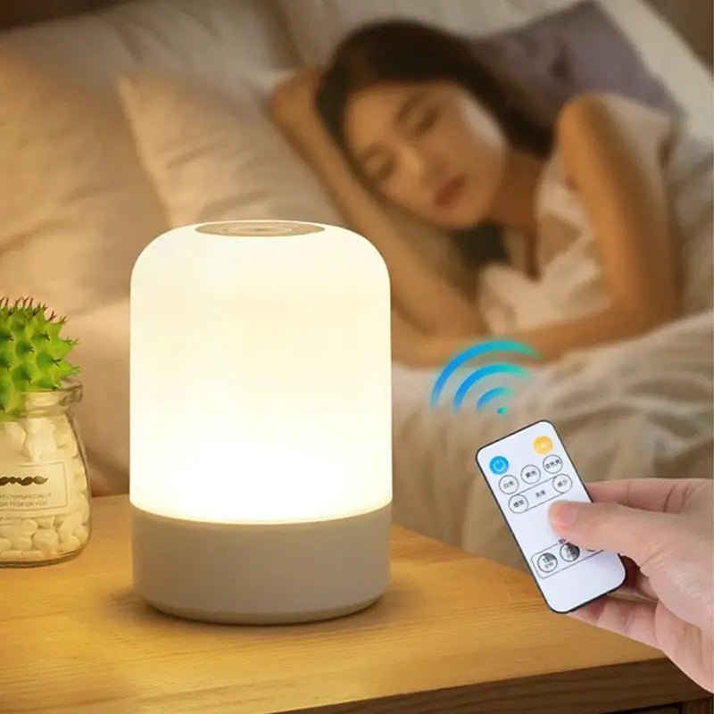 LED night light bedside lamp by Simples Market; white cylindrical touch-dimmable lamp with base on a wooden nightstand.