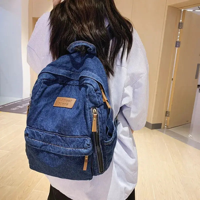 Simples Market denim backpack in blue with multiple pockets and tan zipper pulls