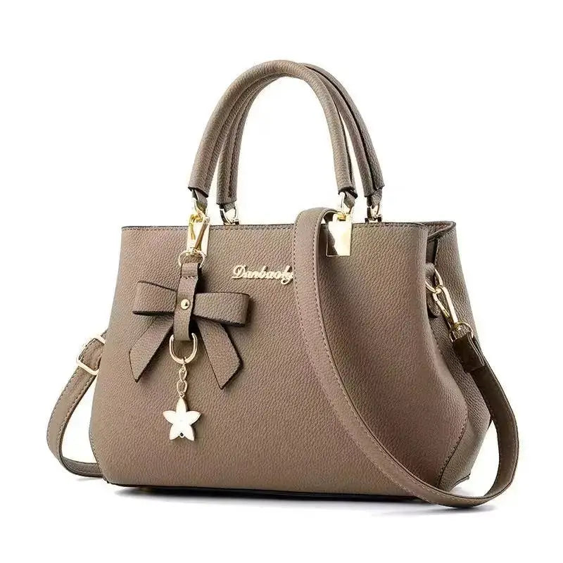 Shoulder bag by Simples Market; taupe bow-detail handbag with top handles and gold hardware crossbody strap.