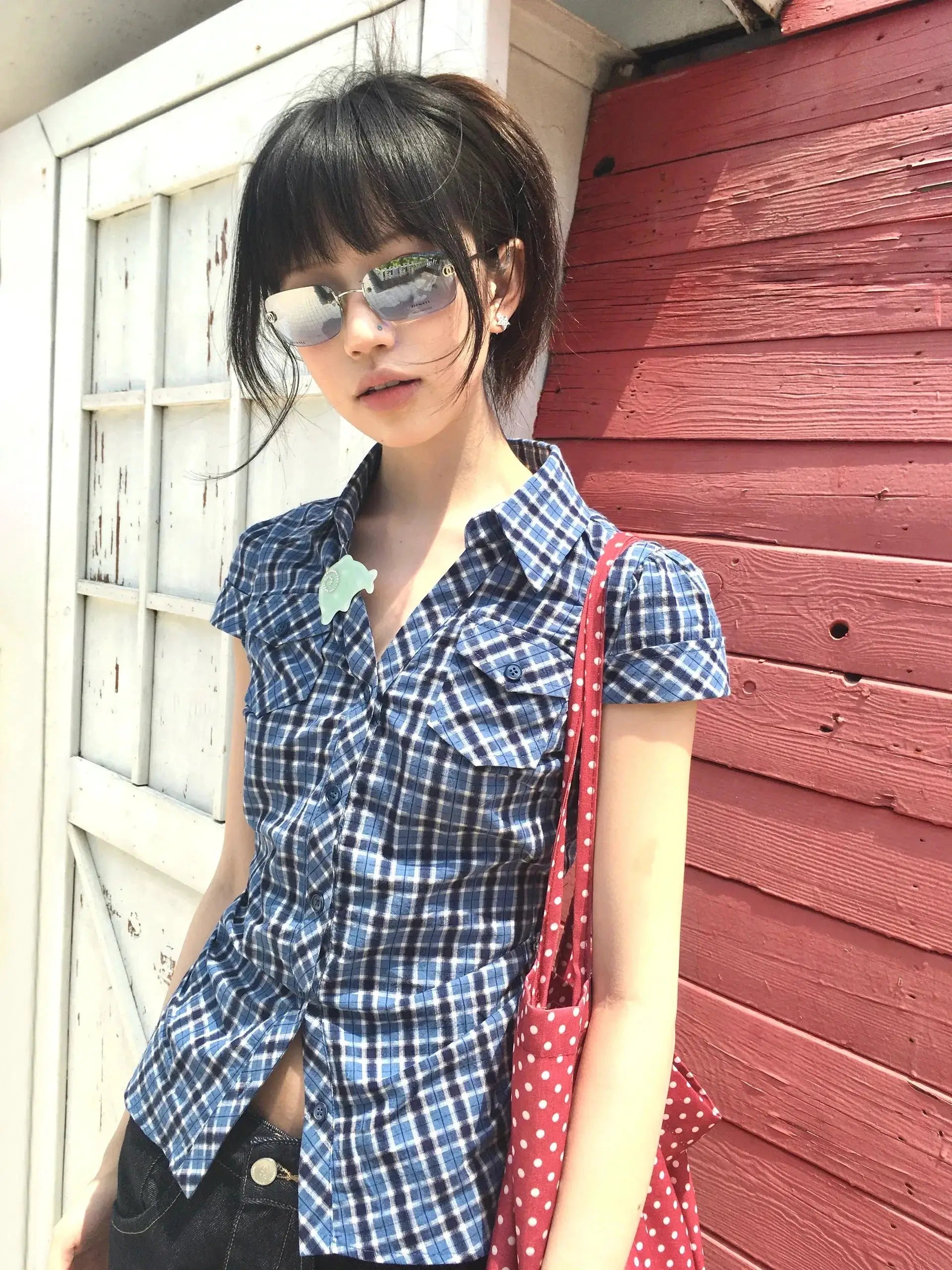 Karrram blue plaid short-sleeve shirt with collar and button-front, paired with a red polka-dot bag