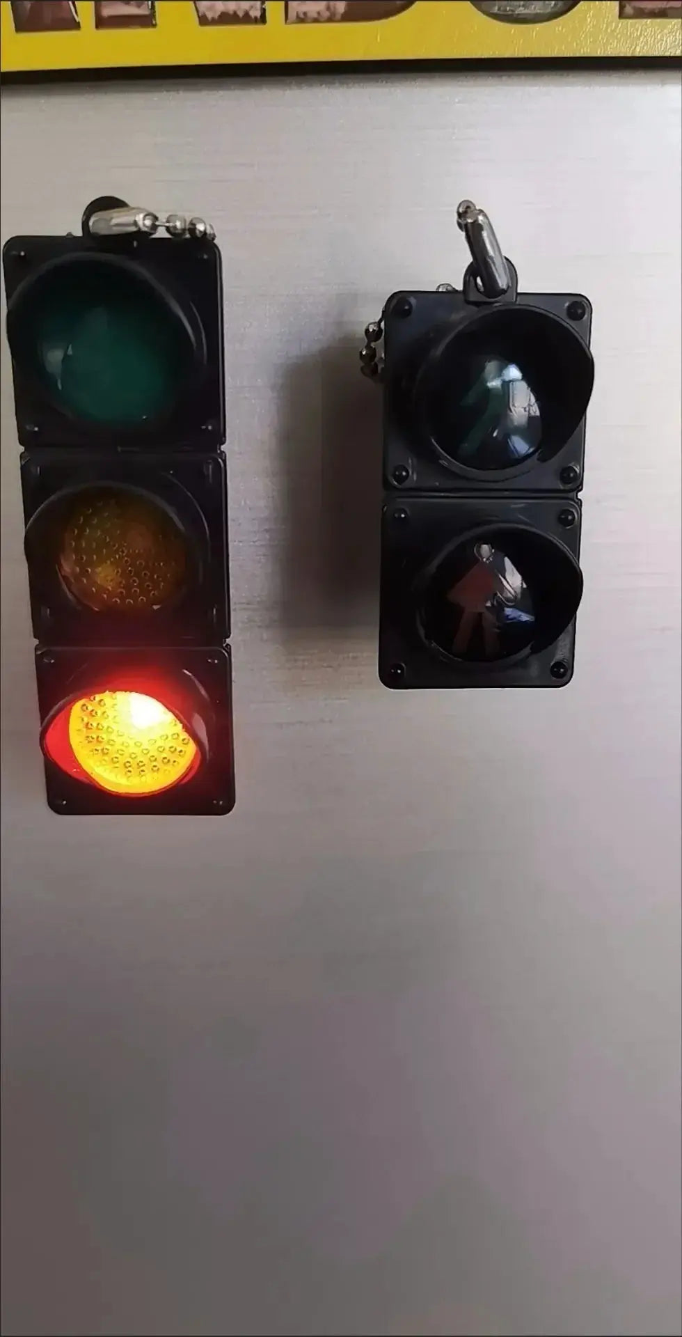 Two traffic light magnetic fridge magnets; left three-light signal shows red, yellow, green in black housings