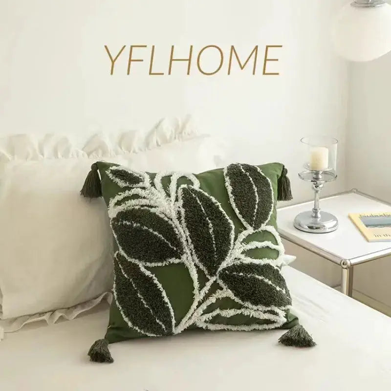 Bohemian green embroidered pillow cover with white leaf pattern and tassel corners; two cushions shown