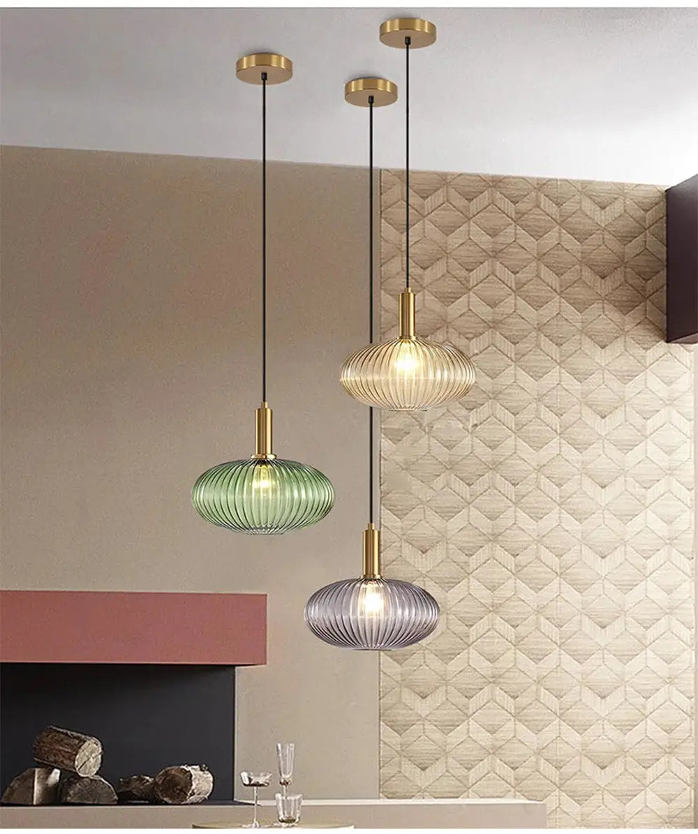 Nordic glass pendant lights trio with ribbed green, cognac amber, and purple glass shades; brass caps and black cords.