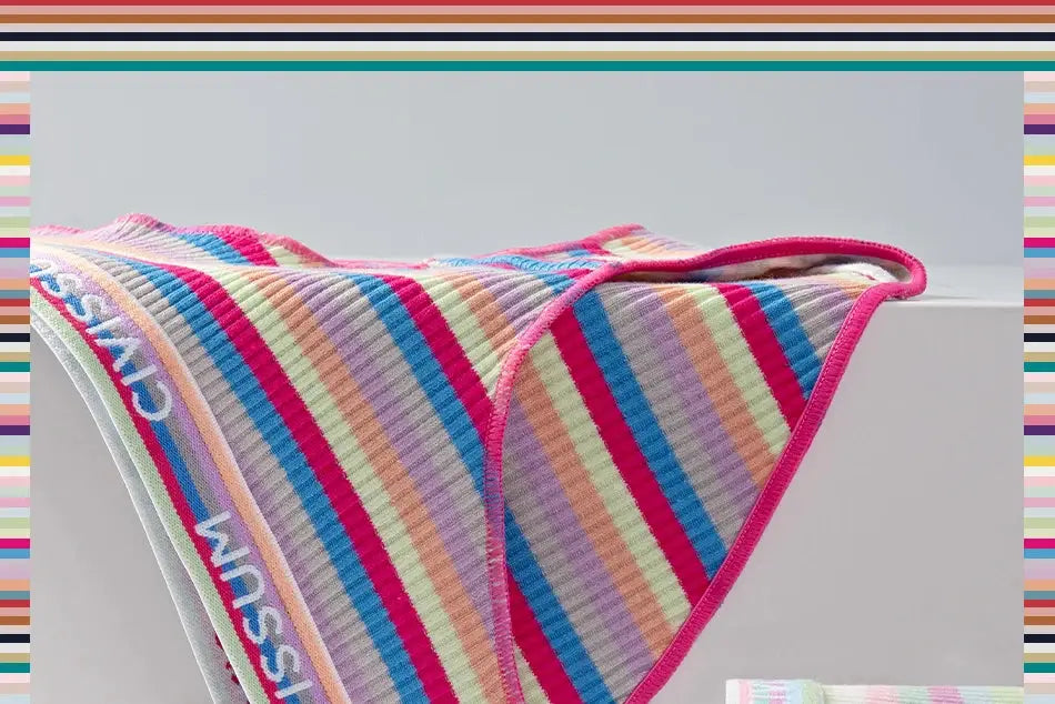 Women cotton panties with rainbow stripes and pink trim, draped over a white ledge