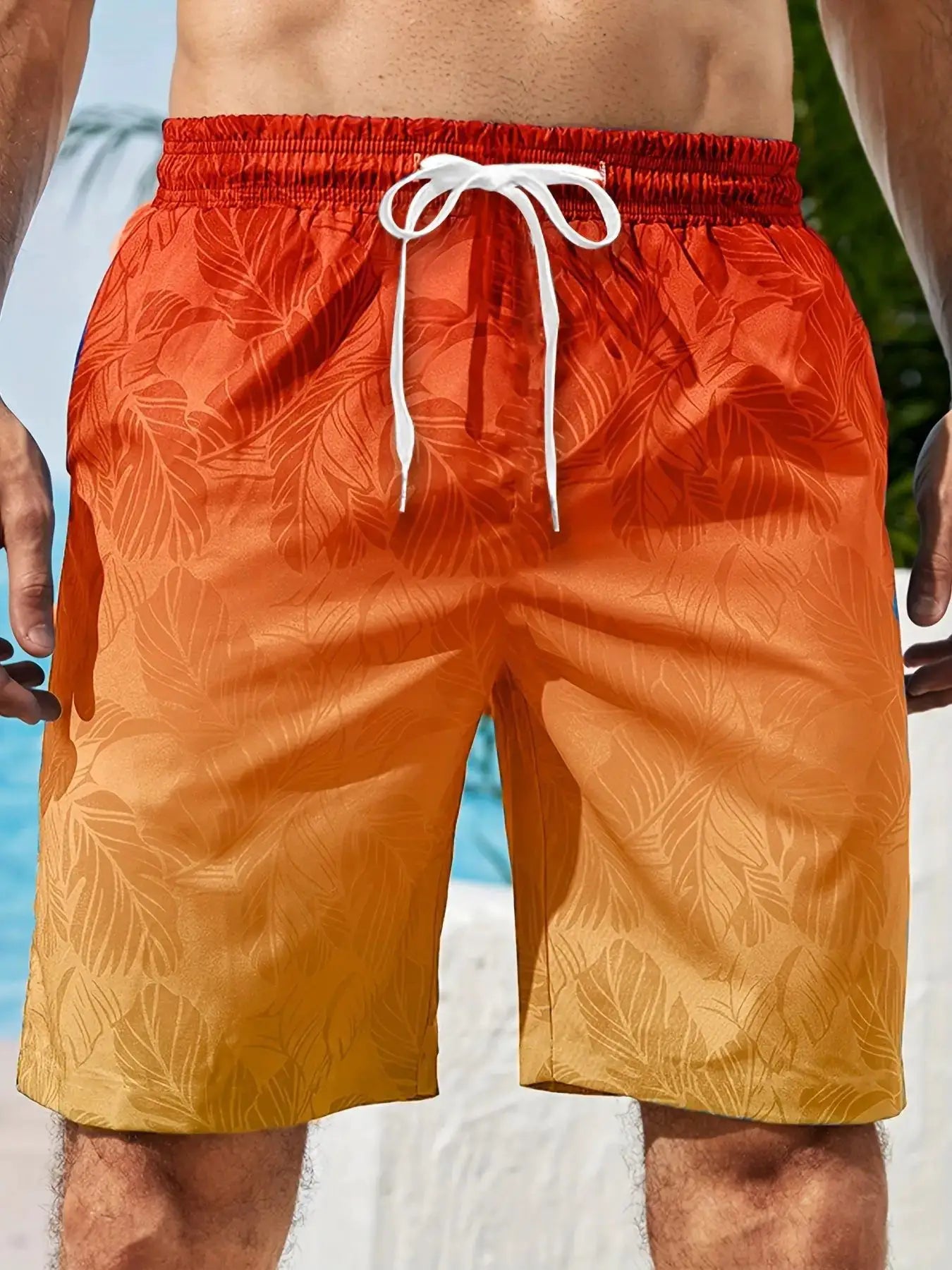 Board shorts orange with tropical leaf pattern and white drawstring, quick-dry swim trunks.