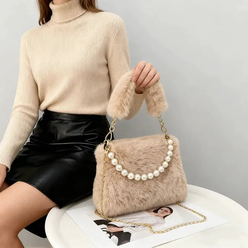 Fashionable pearl-embellished rabbit fur handbag with gold chain crossbody strap in beige.