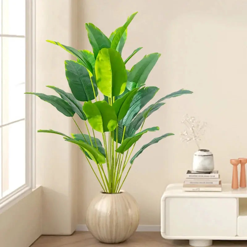 Artificial large tropical palm plant with broad green leaves in a round beige pot, real-touch plastic