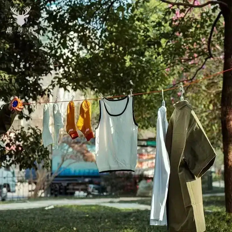 10m retractable clothesline by Simples Market outdoors, with several garments and socks hanging on an orange line