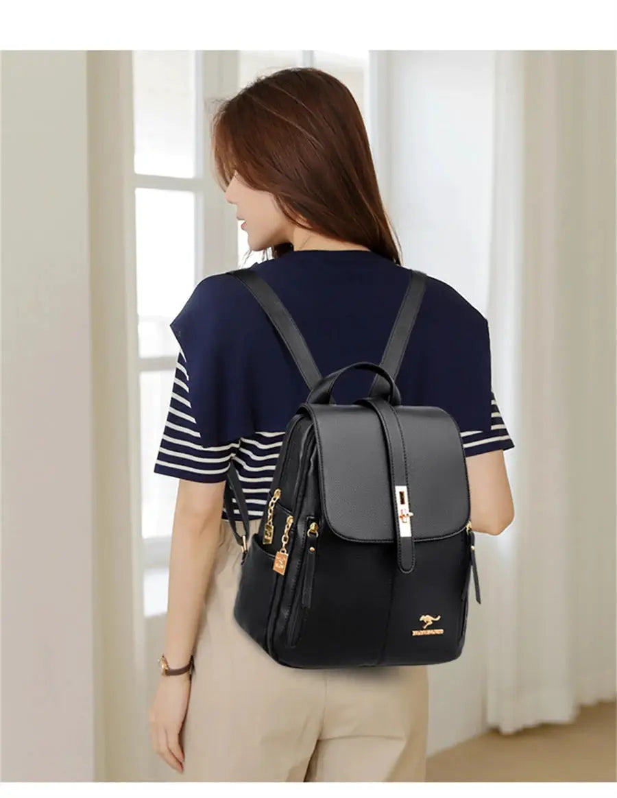 Simples Market black leather backpack with gold hardware and logo worn by a woman; front flap, top handle, zip pockets.