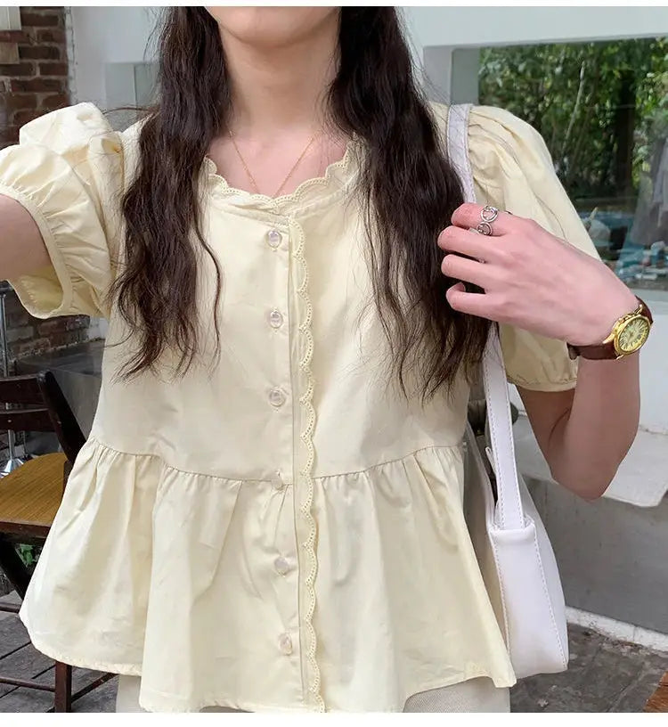 Women's cream-yellow peplum blouse with short puff sleeves, scalloped trim and button front.