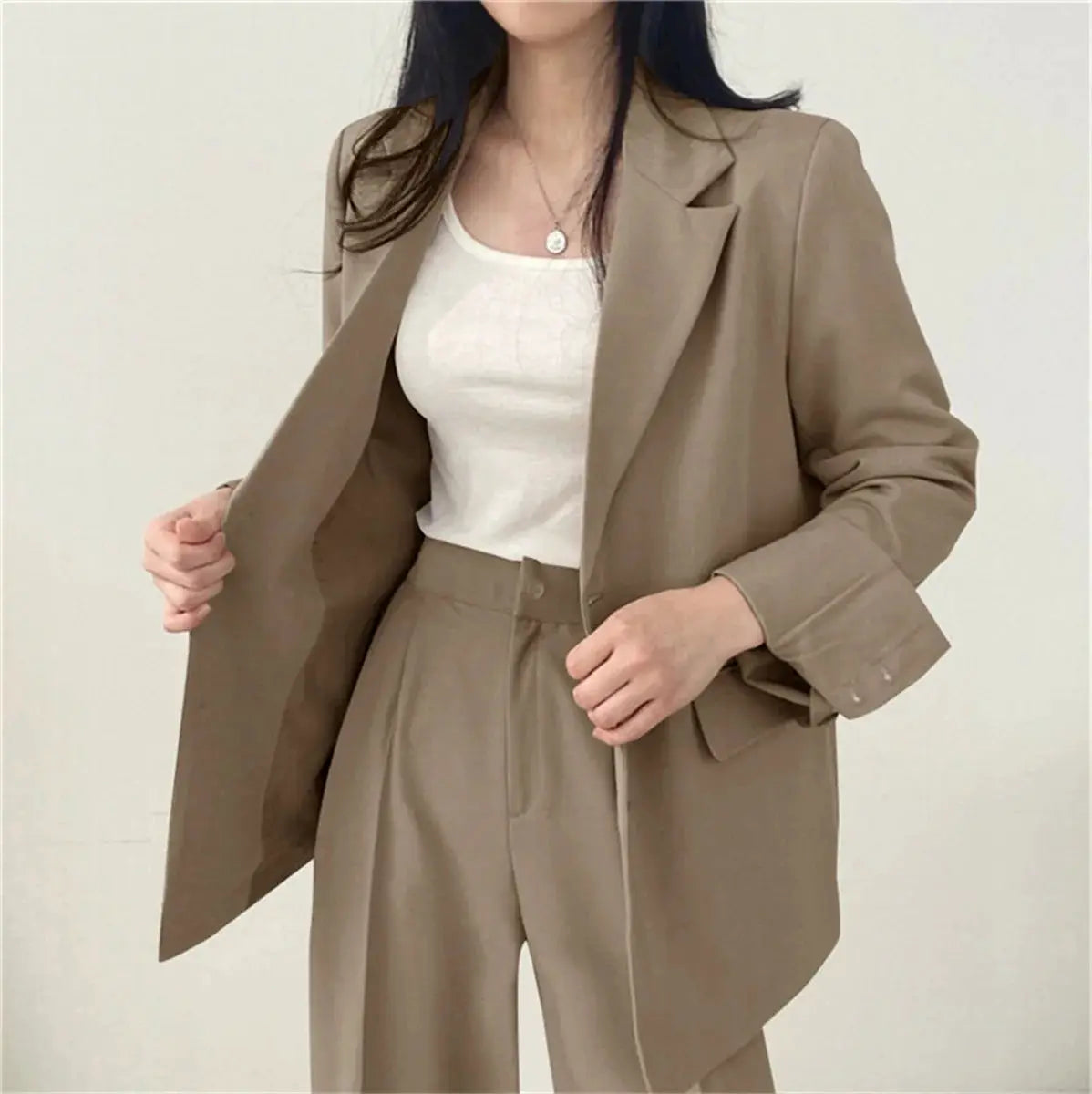 Beige two-piece women's suit: blazer with wide-leg pants worn over a white top