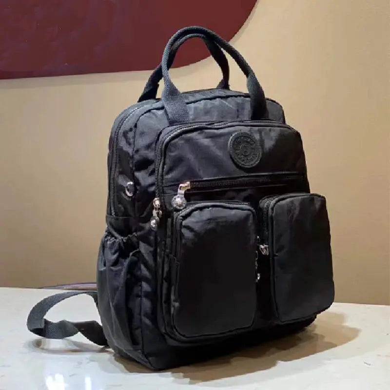 Backpack black nylon with multiple zip pockets, top handles, travel/school bag.