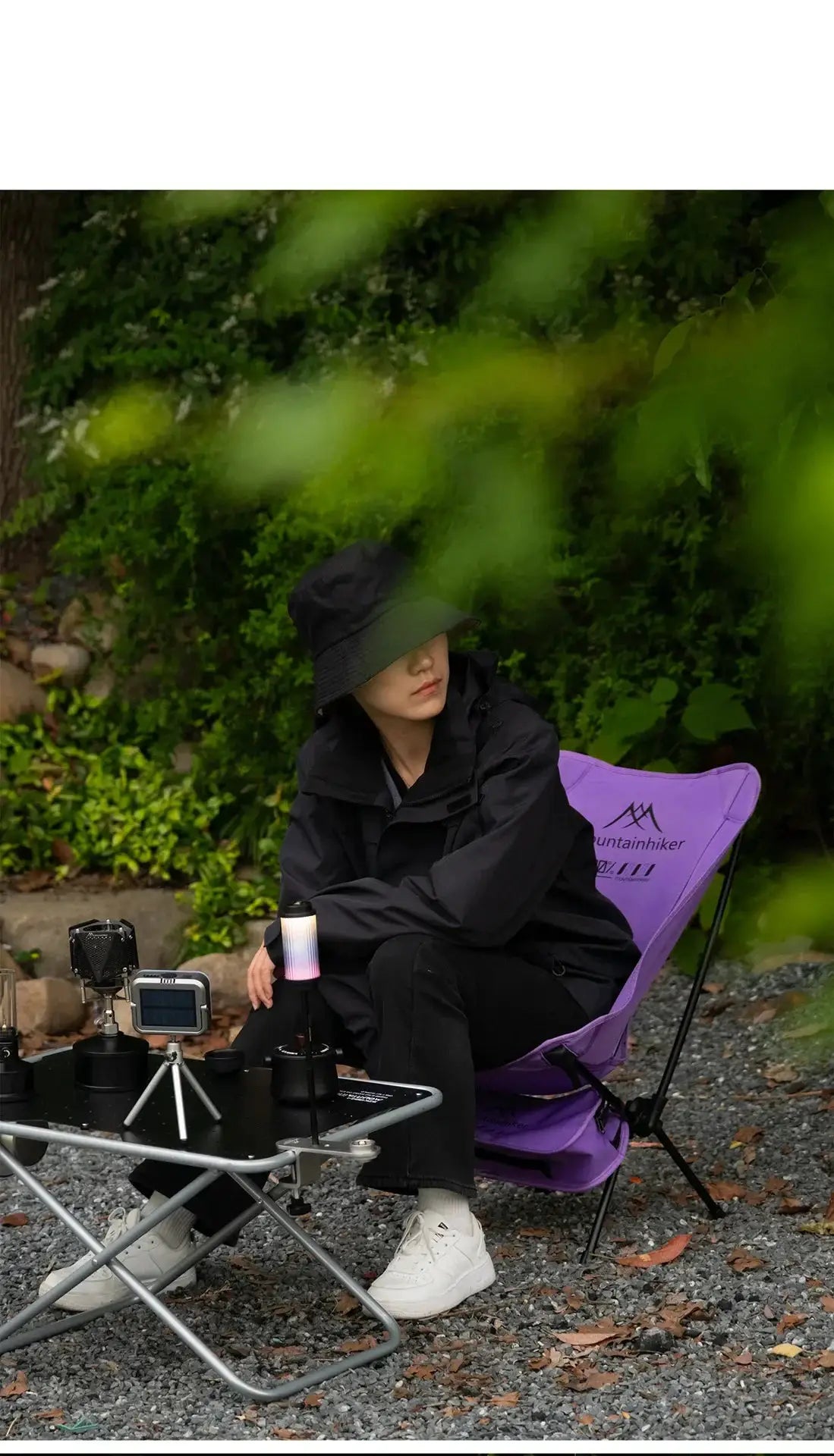 Purple foldable camping chair with outdoor gear on a gravel campsite