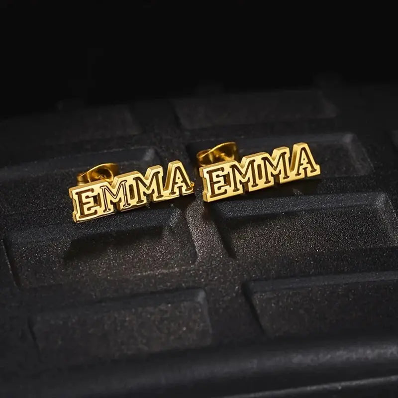 Gold-tone Emma name earrings pair in hollow stainless steel, by Simples Market.