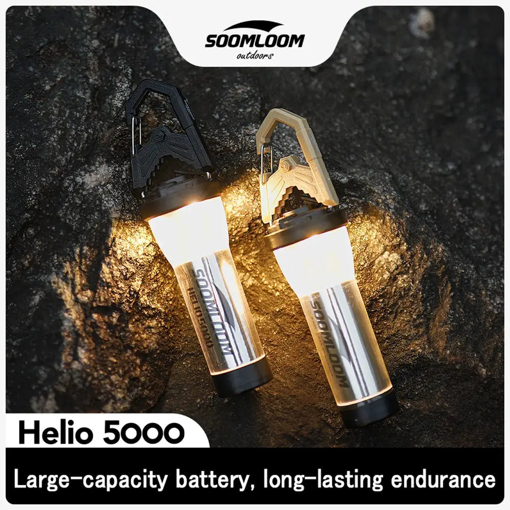 Soomloom Helio 5000 camping lanterns, 2-pack with 5000mAh battery, silver bodies and black/tan handles, lit on rocky terrain