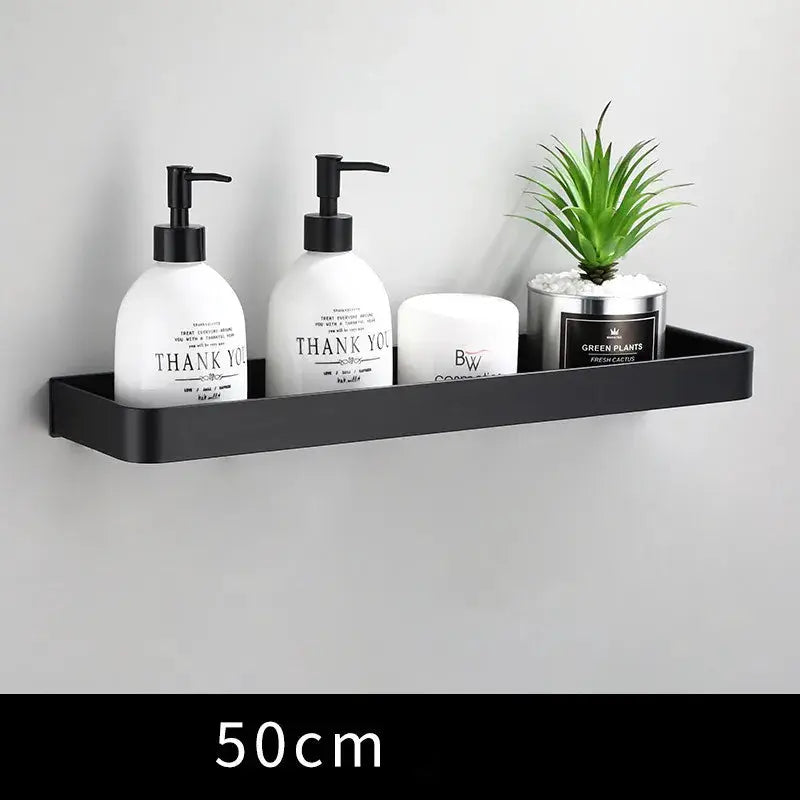 Bathroom wall-mounted black aluminum shelf, 50 cm long, holds four items: two pump bottles, a jar, and a small plant.