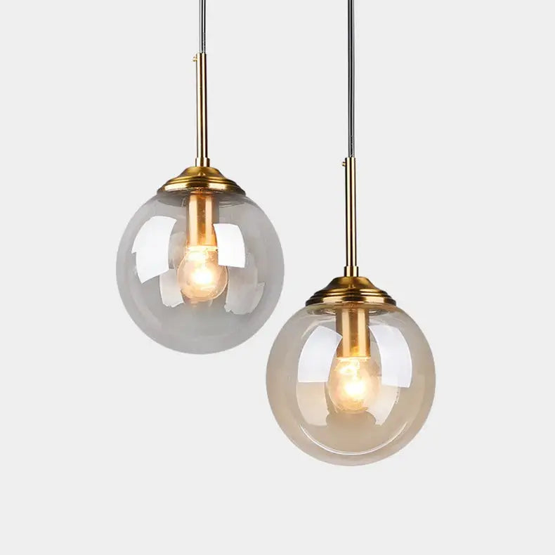 Pendant lamps by Simples Market; modern glass globes with brass accents and dual hanging cords.