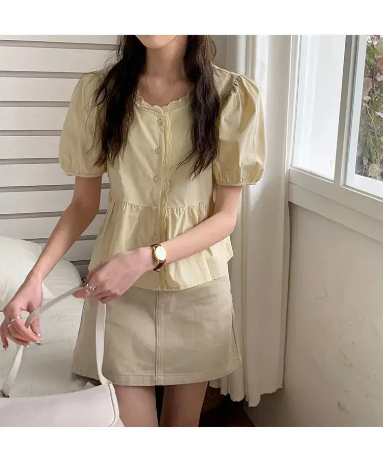 Womens cream puff-sleeve blouse with scalloped neckline and button front, paired with beige mini skirt