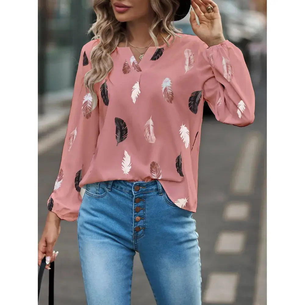 Pink feather-print chiffon blouse for women with long puff sleeves and V-neck, paired with blue jeans.