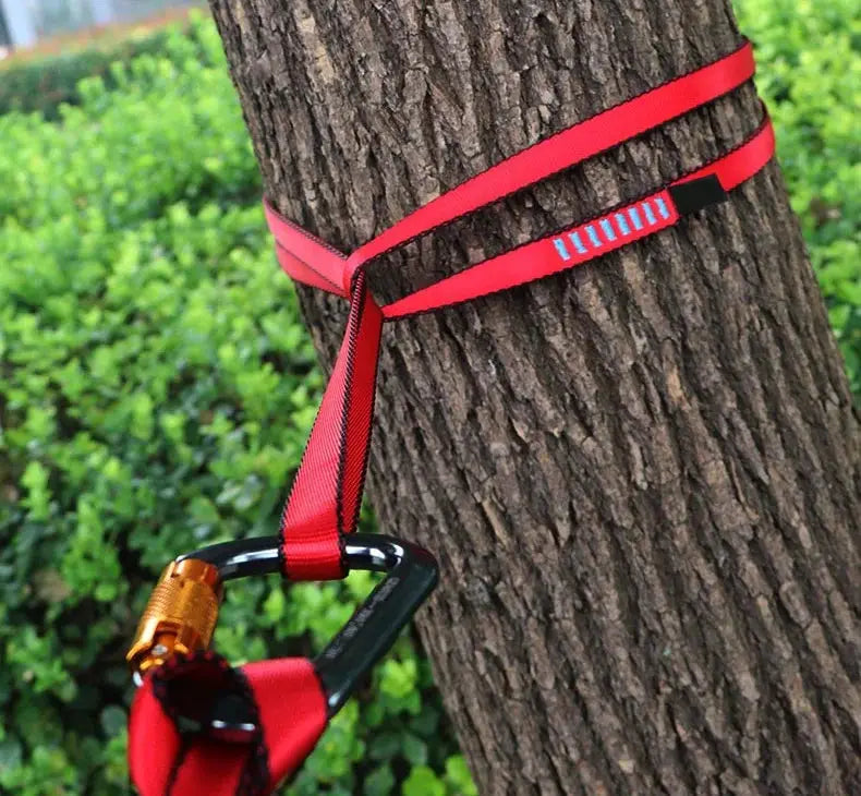 Rock climbing sling belt in red, high-strength polyester with carabiner strapped to a tree.