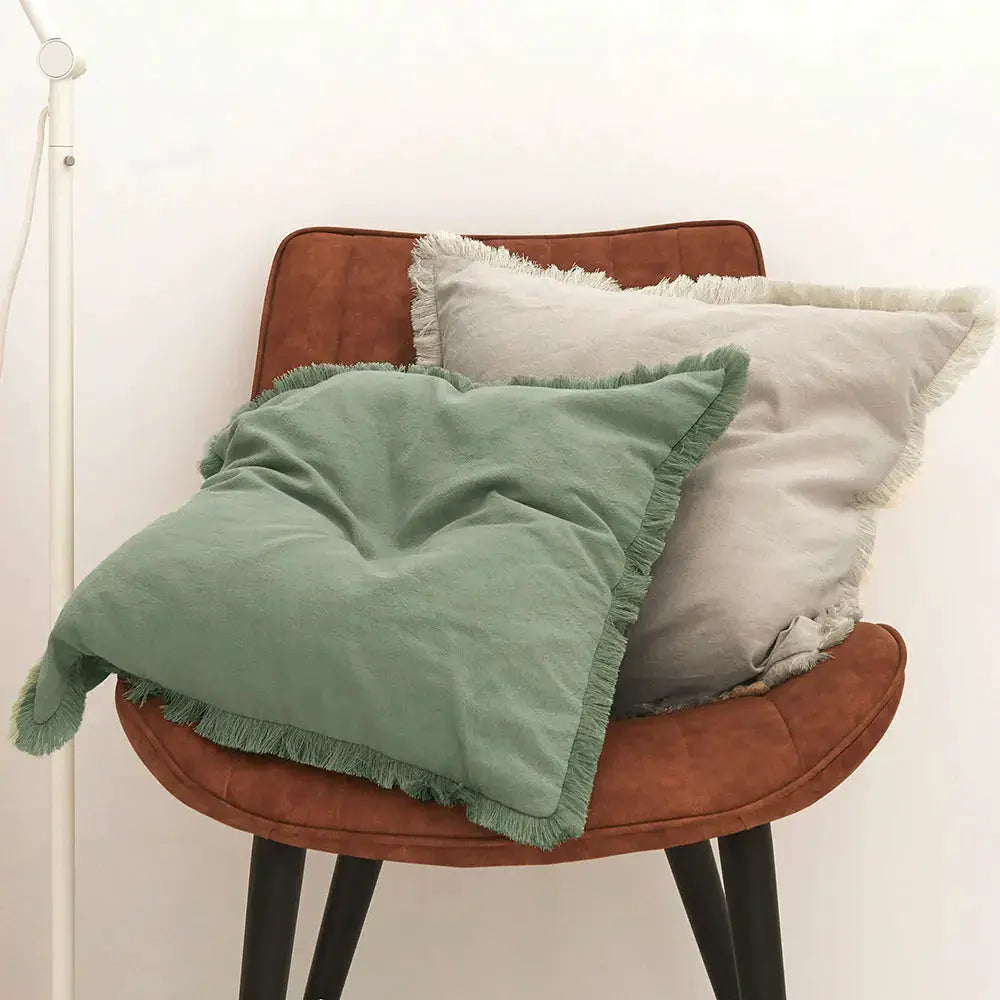 Cushion cover set of 2 with tassels; sage green and light gray fringe pillows on a brown chair.